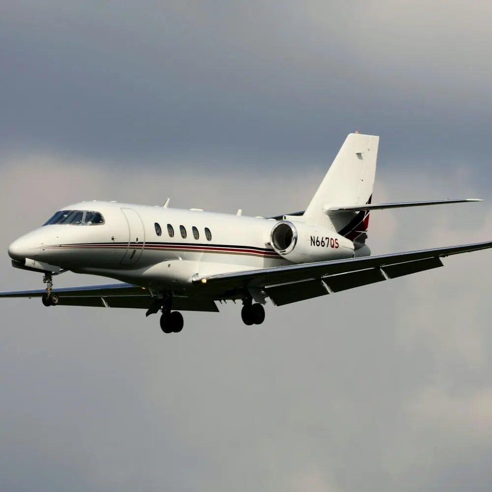 Midsize jet on approach against grey cloud